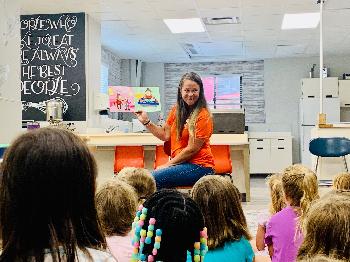 Julie reads “Joe the Money Saves for a Goal” to the younger campers before starting the savings activity. 